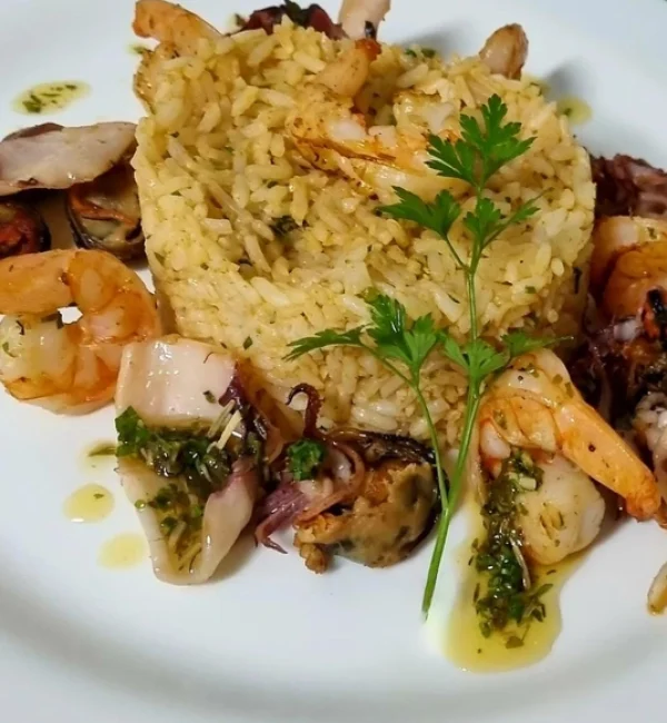 Camarão salteados em vinho branco aromatizado com ervas finas servido com risoto de alho poró e lulas salteadas em molho pesto.redimensionada